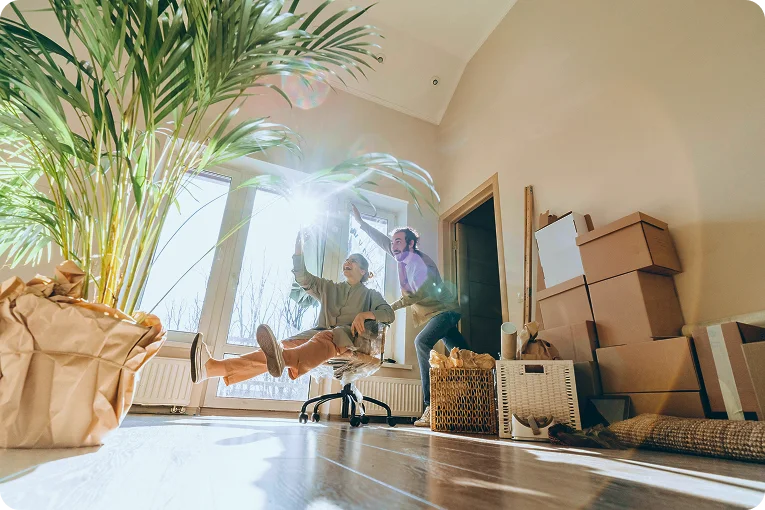 @lang('Casal feliz numa casa nova com caixas de mudança, a brincar após a compra com crédito habitação sem complicações.')
